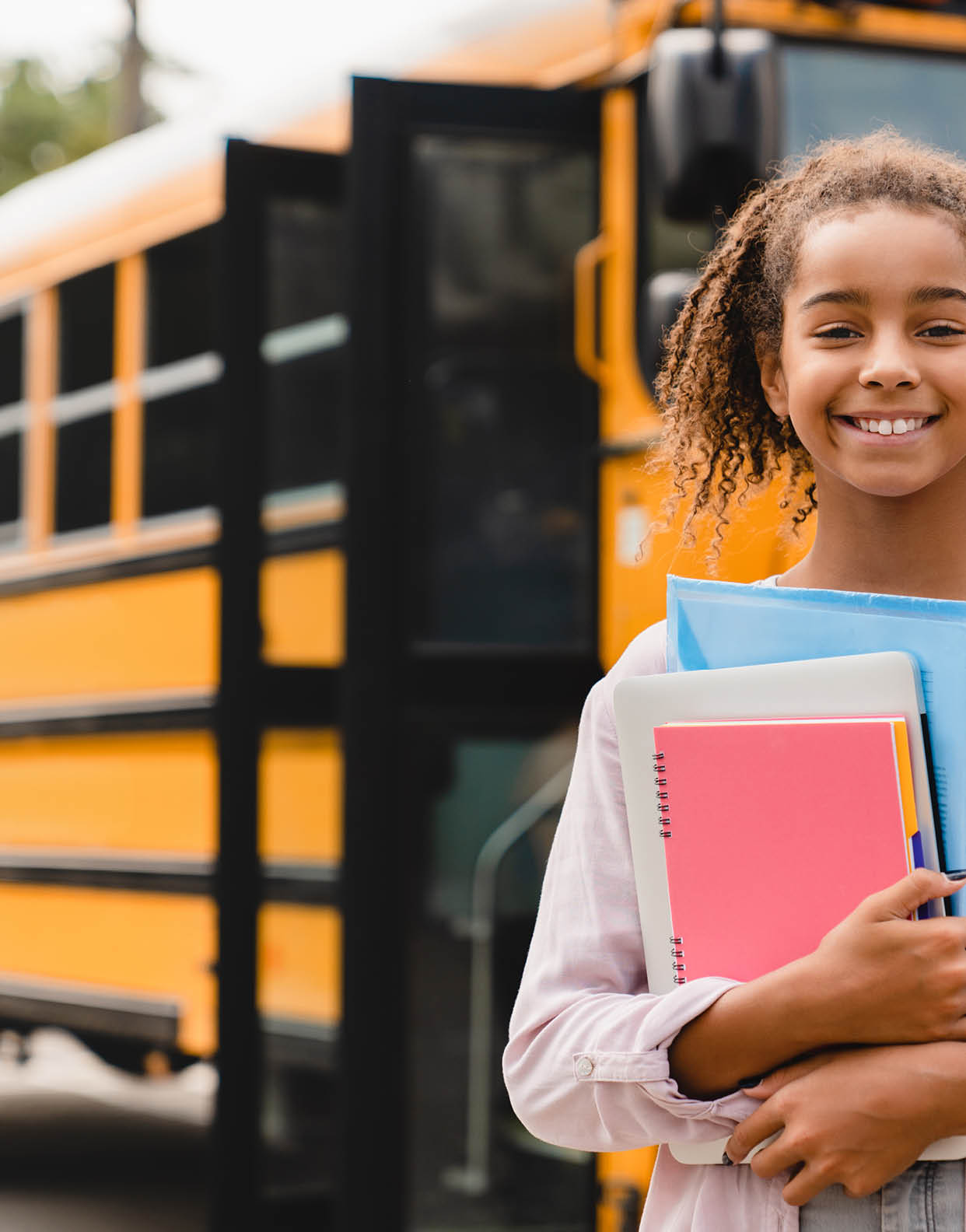 Smiling african-american schoolgirl going back to school with books and copybooks waiting for schoolbus  New academic year semester