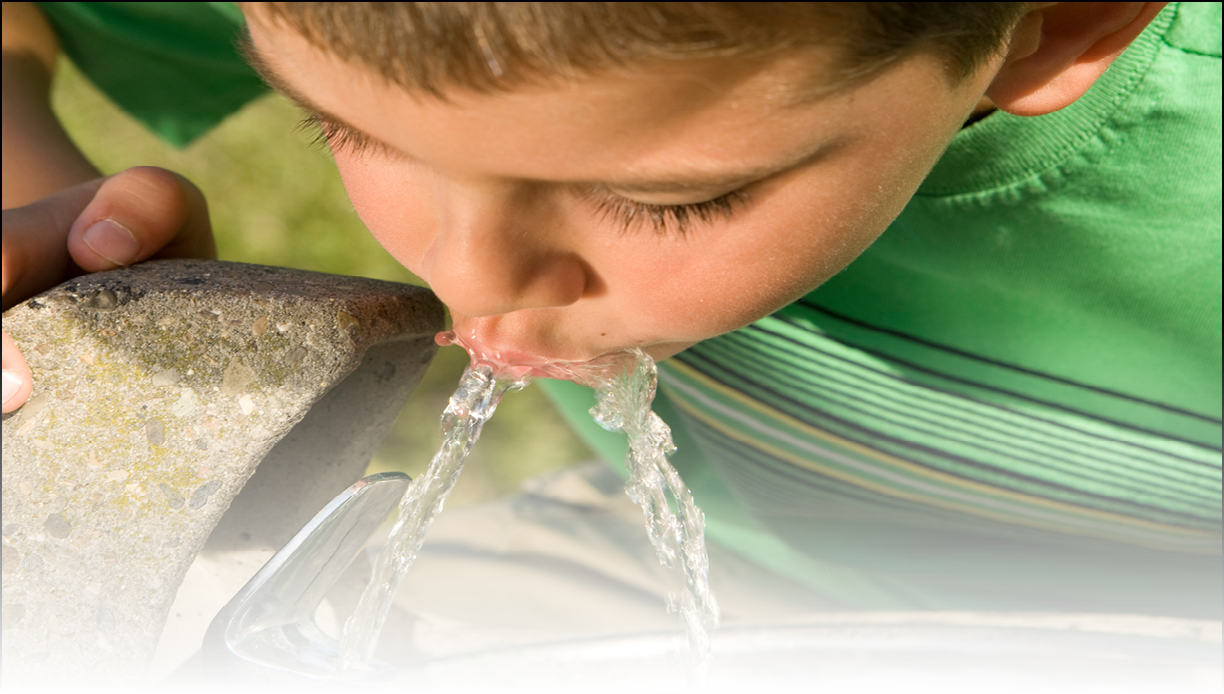 Little boy drinking from a fountain