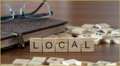 local word or concept represented by wooden letter tiles on a wooden table with glasses and a book